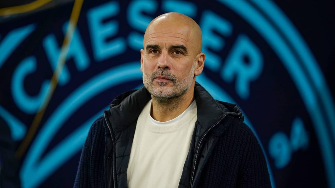Pep Guardiola with Man City badge in background