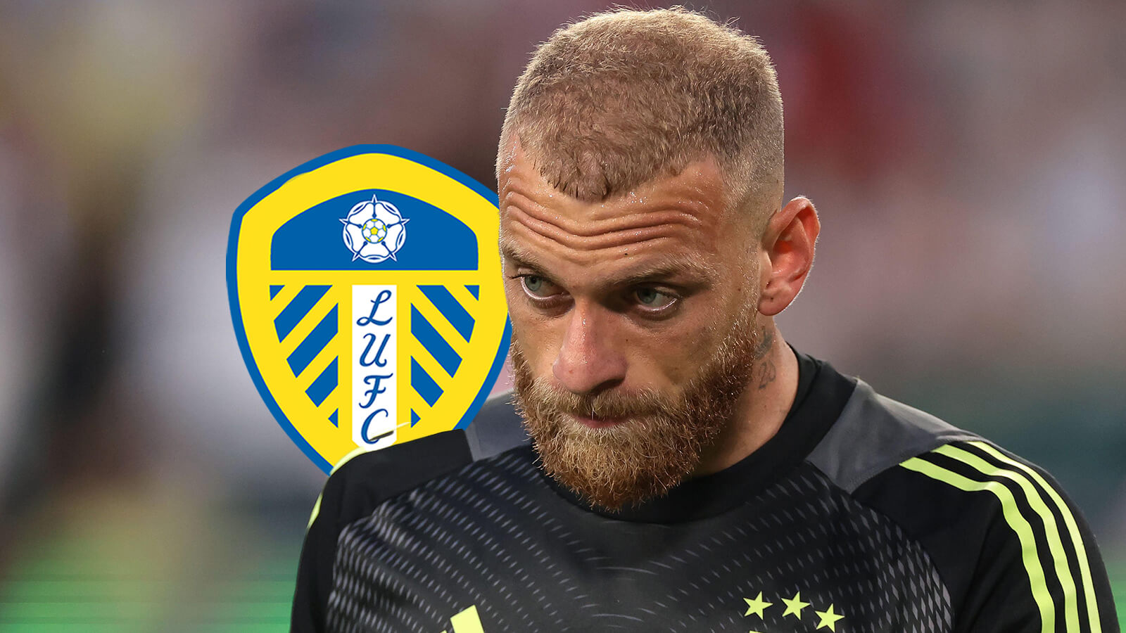 Michele Di Gregorio looks glum, with a Leeds United badge next to him